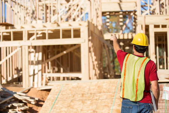 Construction engineer reviewing plans beside a building under construction