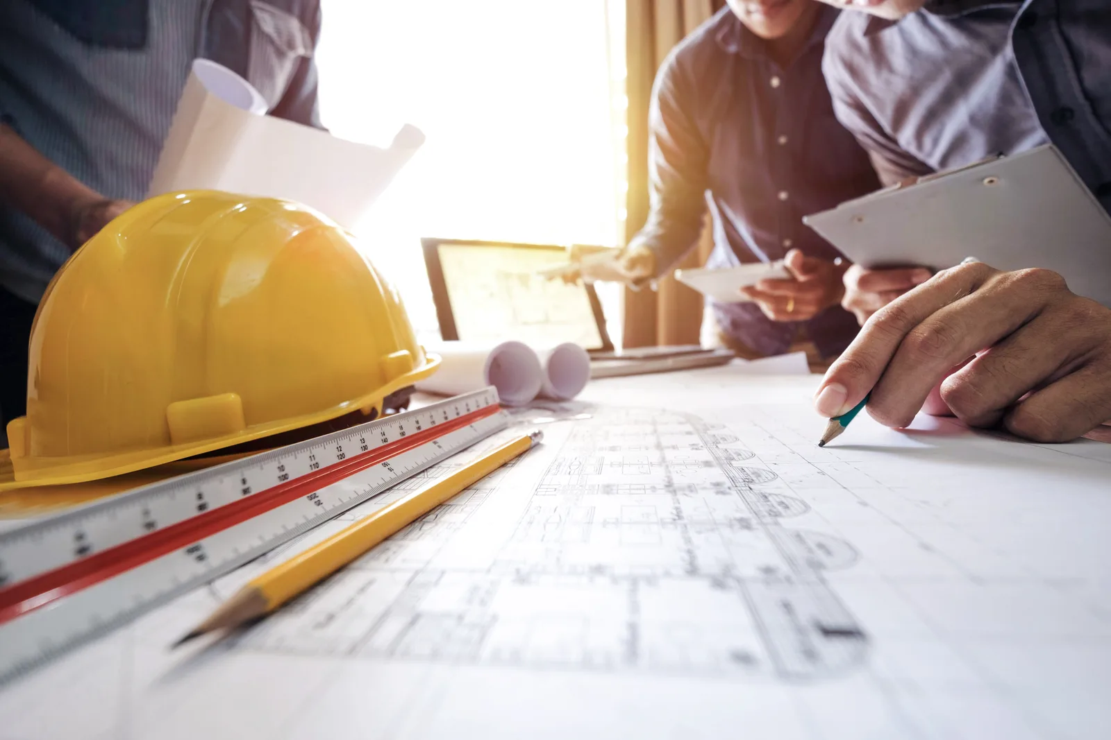 Construction team reviewing drawings with a hard hat on the table