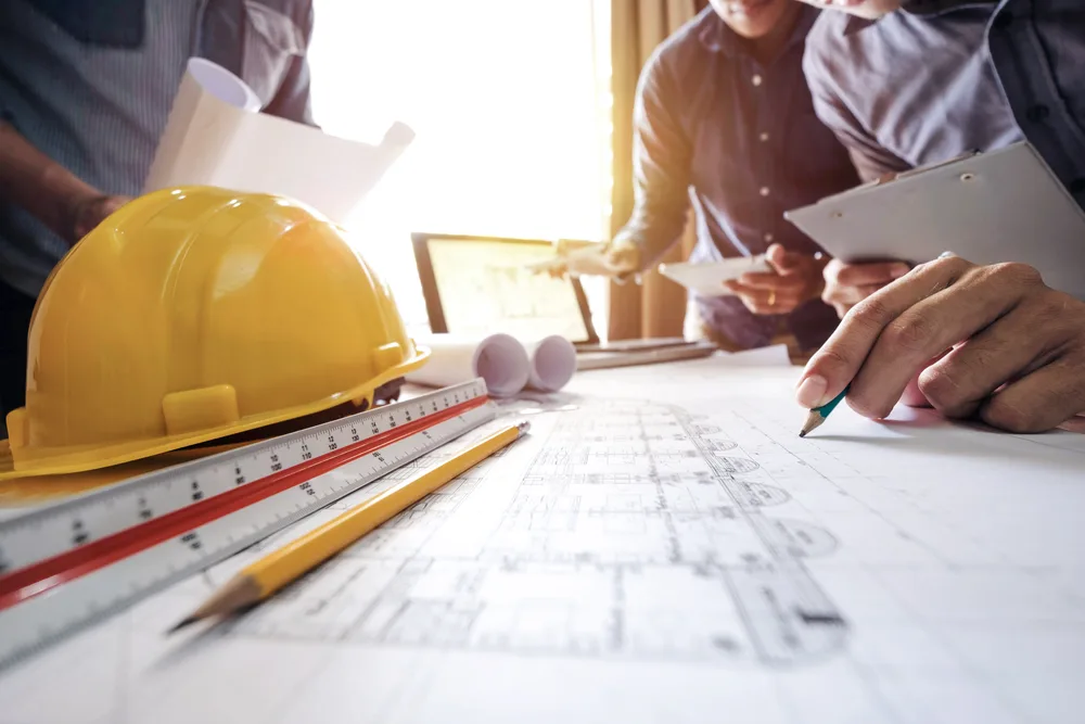 Hard hat and drawings on a table during program planning